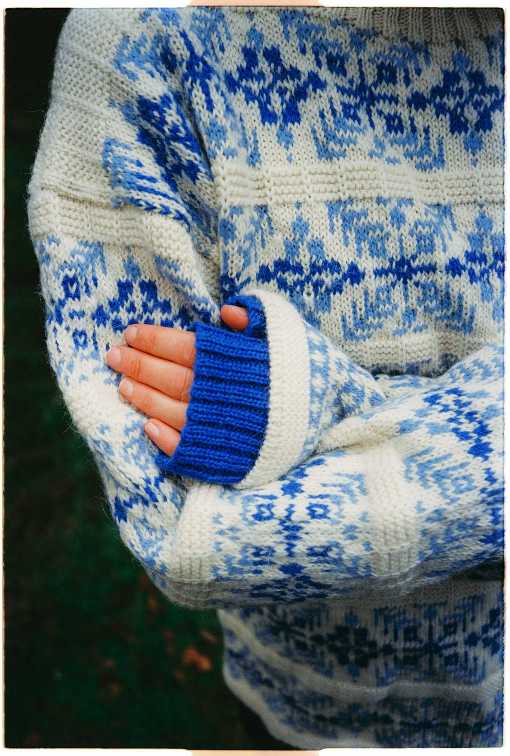 Close-up of a person wearing a blue and white patterned sweater with a blurred background